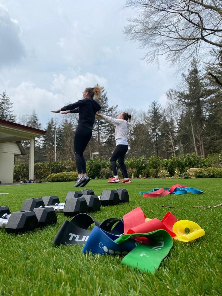Groep vrouwen traint buiten met materiaal op het gras